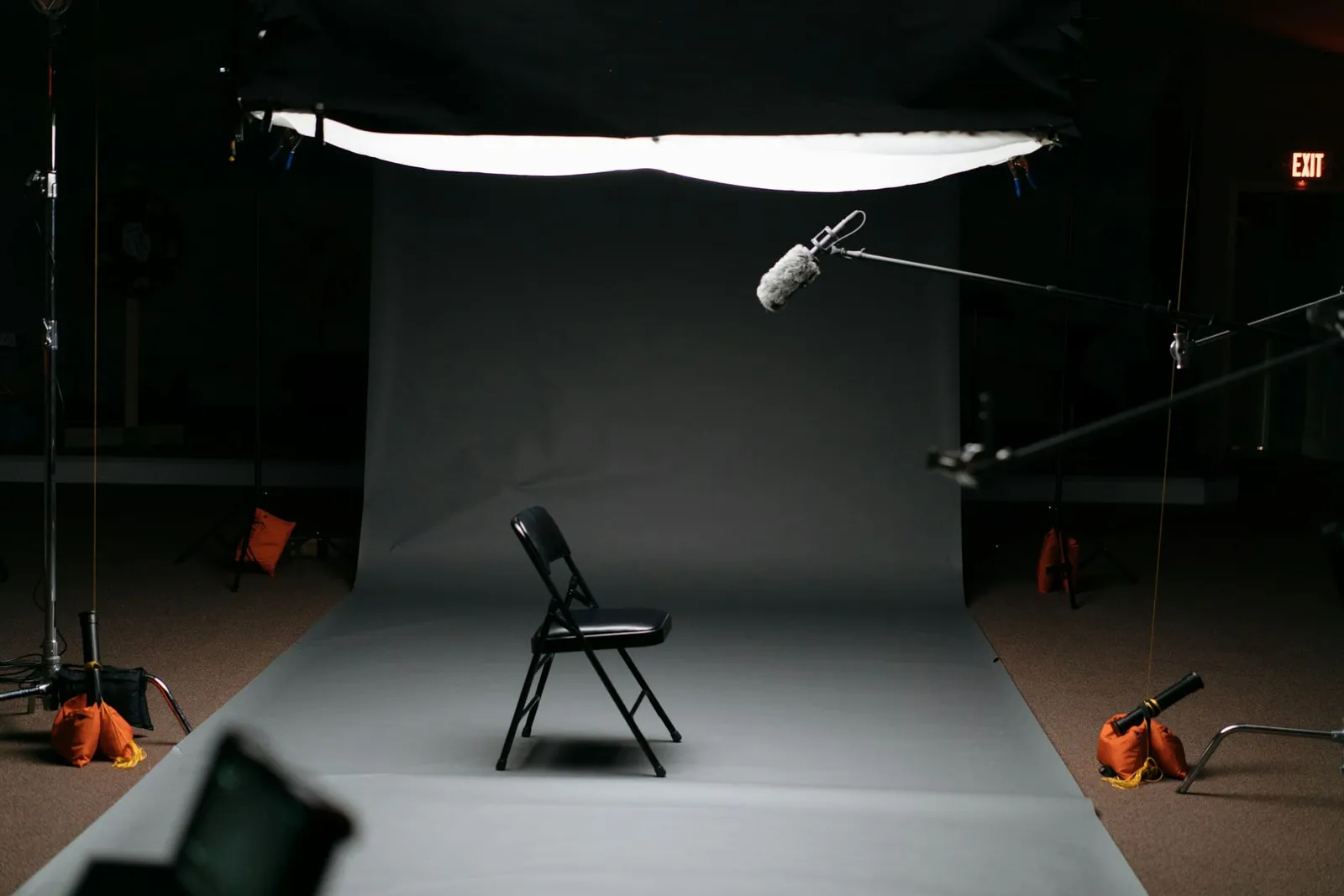 Dunkles Fotostudio mit Hintergrund, Stuhl und Leuchten