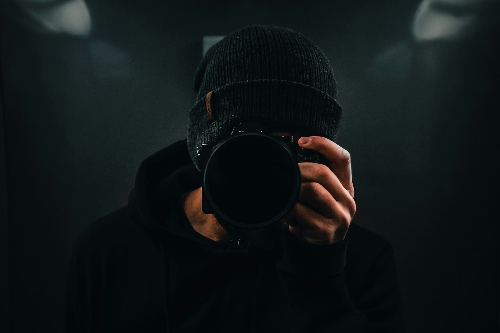 Fotograf mit Kamera vor dem Gesicht im Dunkeln