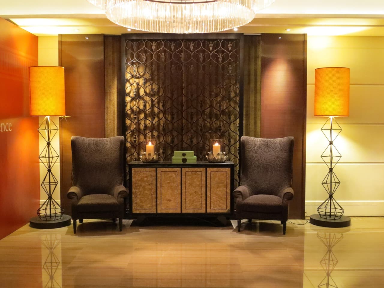 Dunkle Hotellobby am Abend mit Messingleuchte, Ledersessel und leerem Gang