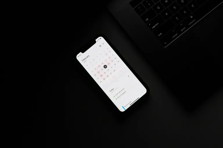 Smartphone mit Kalender auf einem dunklen Tisch