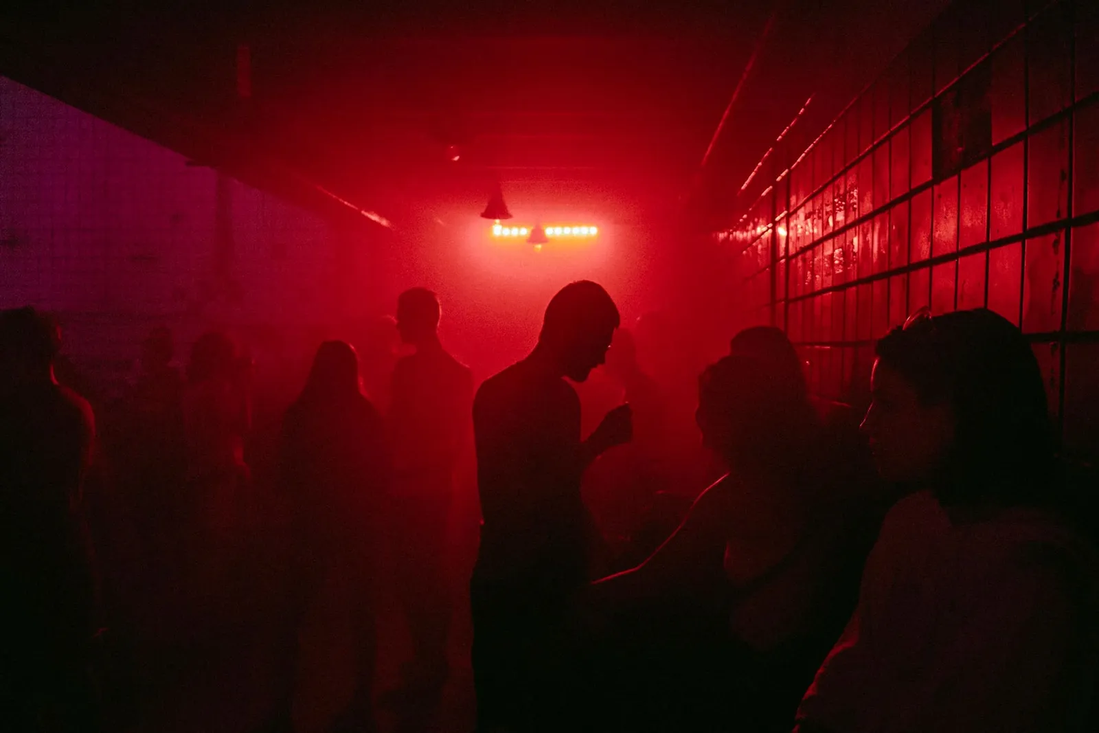 Silhouetten von Gästen in rotem Clublicht