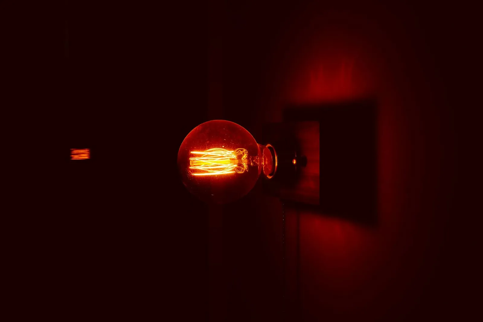 Glühbirne an einer Wand in einem dunklen, rot beleuchteten Raum