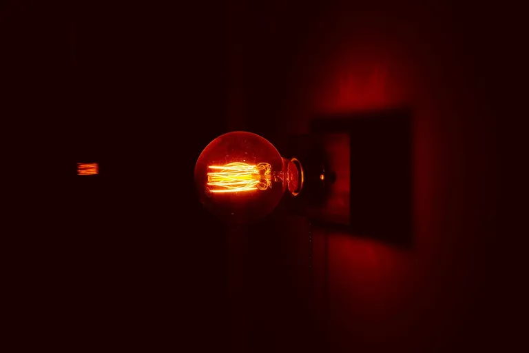 Glühbirne an einer Wand in einem dunklen, rot beleuchteten Raum