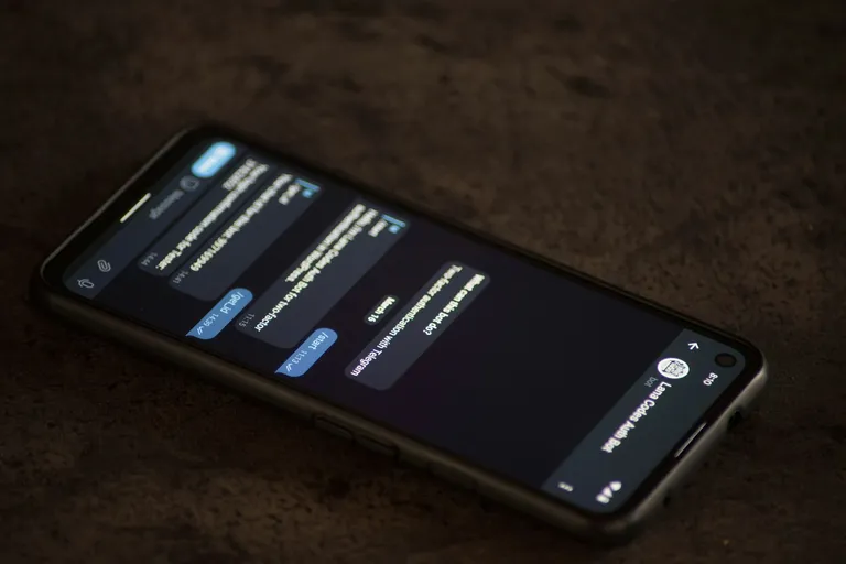 Smartphone mit Nachrichtenverlauf auf einem dunklen Tisch