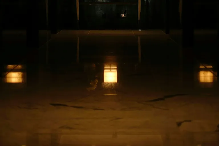 Dunkle Hotellobby mit warm leuchtenden Tischlampen