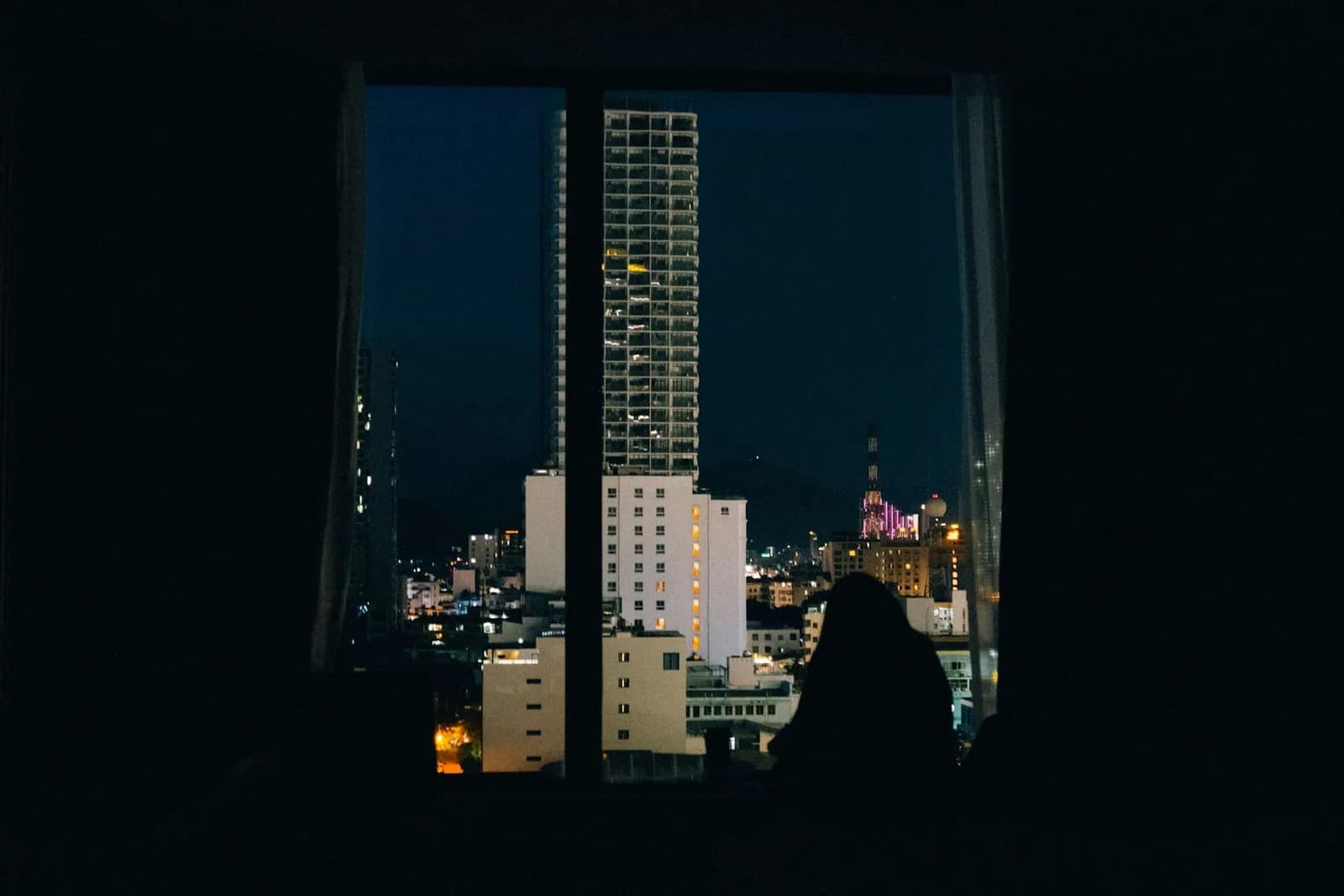 Silhouette am Fenster vor der nächtlichen Stadt
