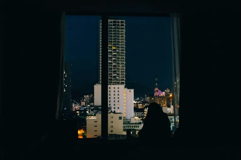 Silhouette am Fenster vor der nächtlichen Stadt