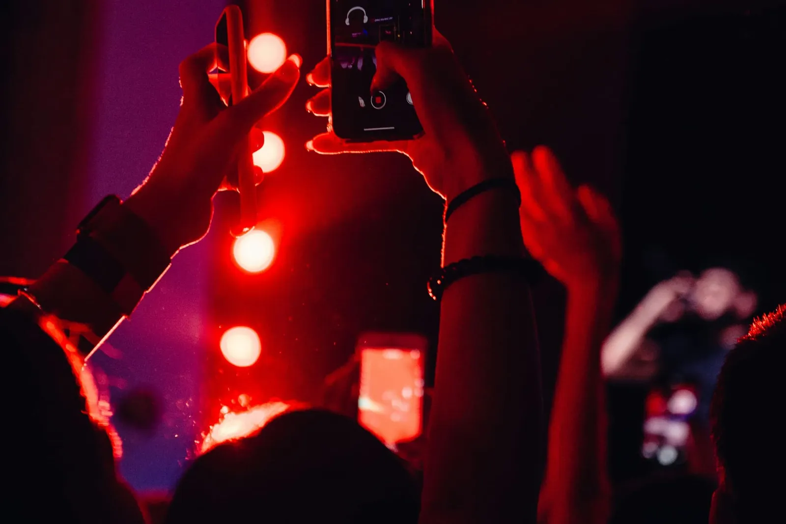 Smartphones filmen eine Bühne im roten Licht