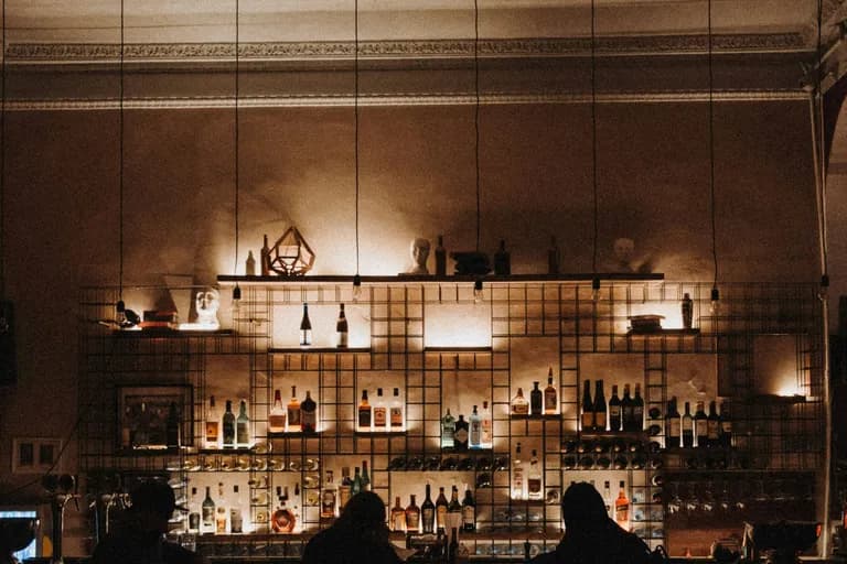 Silhouetten von Gästen vor einer beleuchteten Bar