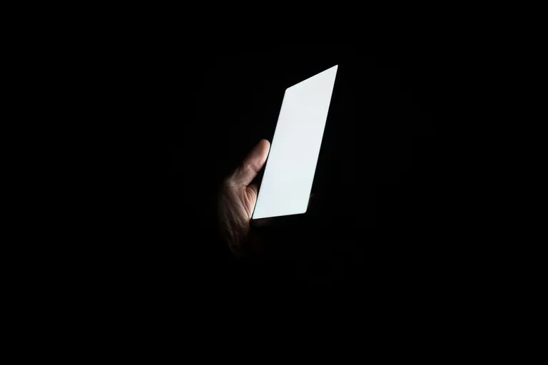 Leuchtendes Smartphone in einer Hand im Dunkeln