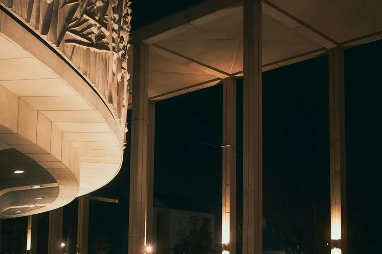 Dunkles Hallenbad mit warm beleuchteten Säulen bei Nacht