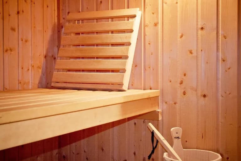 Leerer Saunaraum aus hellem Holz mit gestapelten Handtüchern und warmem Licht