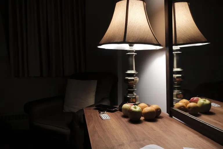 Hotelzimmer bei Nacht mit Tischlampe, Spiegel und Obstschale