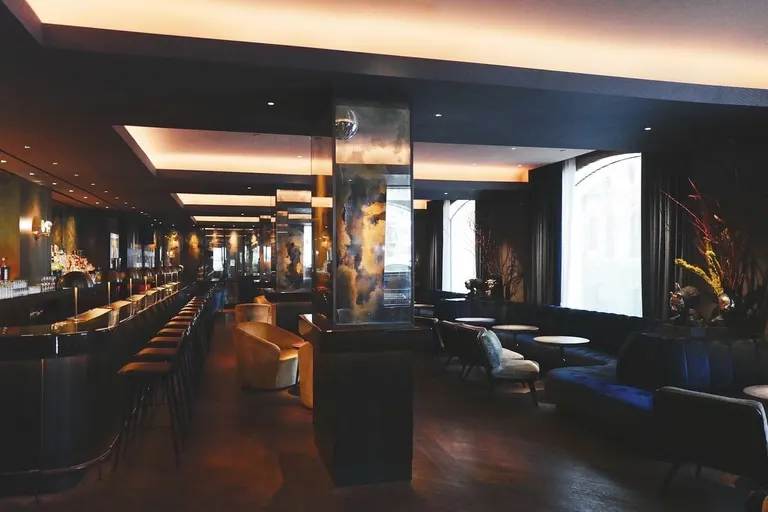 Dunkle Lounge mit langer Bar, Sitzgruppen und indirektem Licht
