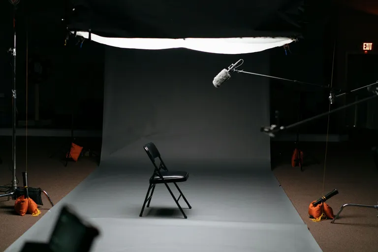 Dunkles Fotostudio mit Hintergrund, Stuhl und Leuchten